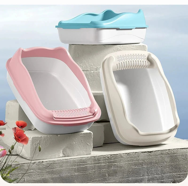 Three stylish cat litter boxes in pink, blue, and white, displayed on light-colored blocks against a blue sky backdrop.