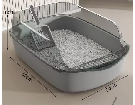 A gray cat litter box with a scoop resting inside, filled with light-colored litter, illuminated softly from above.