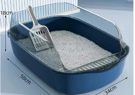 A Blue cat litter box with a scoop resting inside, filled with light-colored litter, illuminated softly from above.