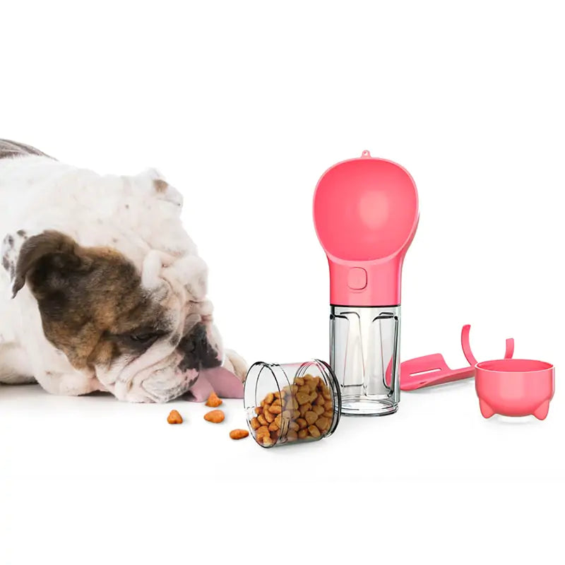 A bulldog curiously licks kibble from the floor, beside a pink pet food dispenser and storage container.