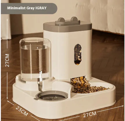 A minimalist gray pet feeder and water dispenser, with a transparent water reservoir and kibble dispensing area, set on a wooden floor.