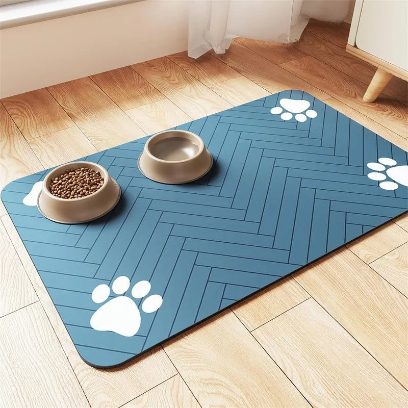A blue pet mat with herringbone pattern, featuring two beige bowls, one filled with kibble and paw prints in the corners.
