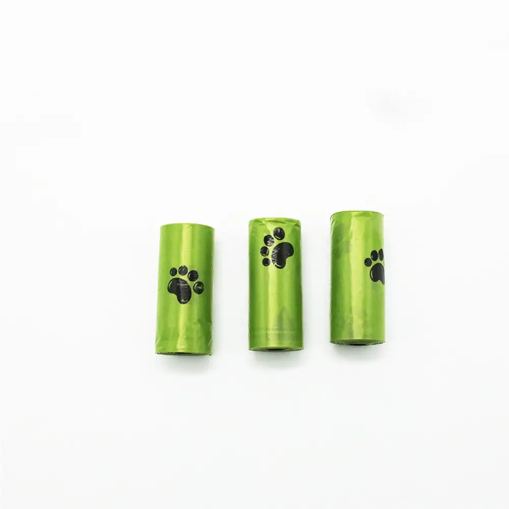 Three green pet waste bag rolls with black paw print designs on the sides, arranged side by side on a white background.