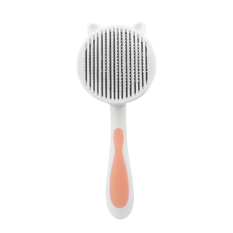 Cute cat-themed grooming brush with a round head, featuring fine comb teeth and a comfortable handle in white and peach colors.