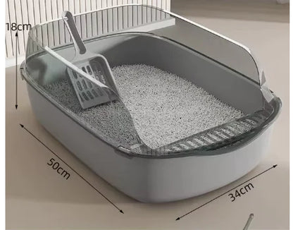 A gray cat litter box with a scoop resting inside, filled with light-colored litter, illuminated softly from above.