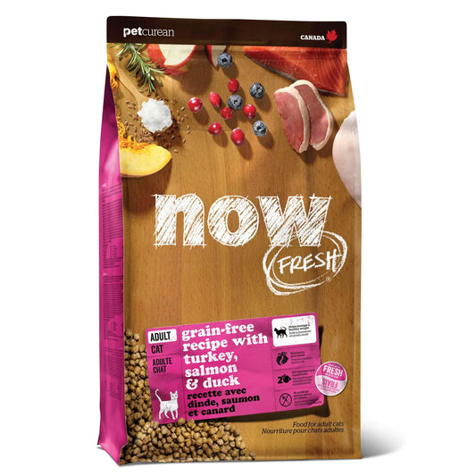 A bag of NOW FRESH cat food featuring a grain-free recipe with turkey, salmon, and duck, set against a wooden background.