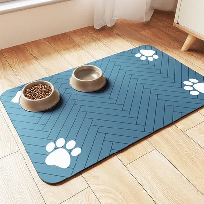 A blue pet mat with herringbone pattern, featuring two beige bowls, one filled with kibble and paw prints in the corners.