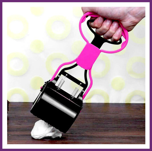 A person holds a pink and black pooper scooper on a wooden surface with a patterned background.