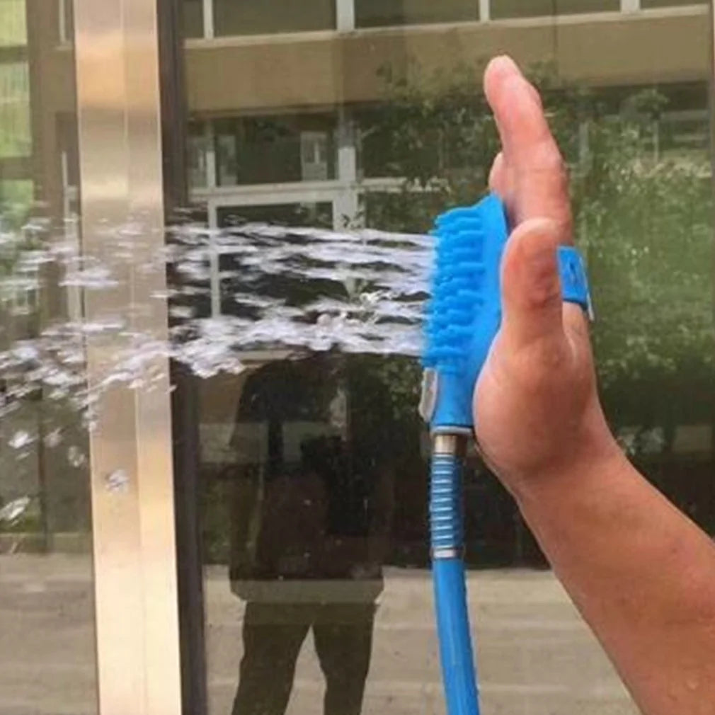 A hand holding a blue water sprayer, directing a spray of water towards a glass surface, with reflections visible in the glass.