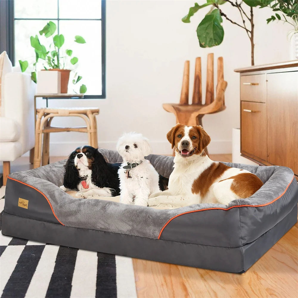 Three dogs on a large gray pet bed in a living room setting.