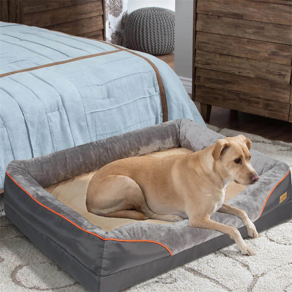 Dog sitting on a large gray pet bed in a bedroom setting.